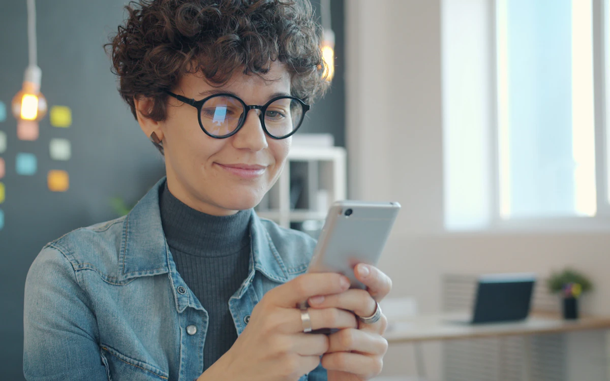 A woman smiling while reading a message on her phone