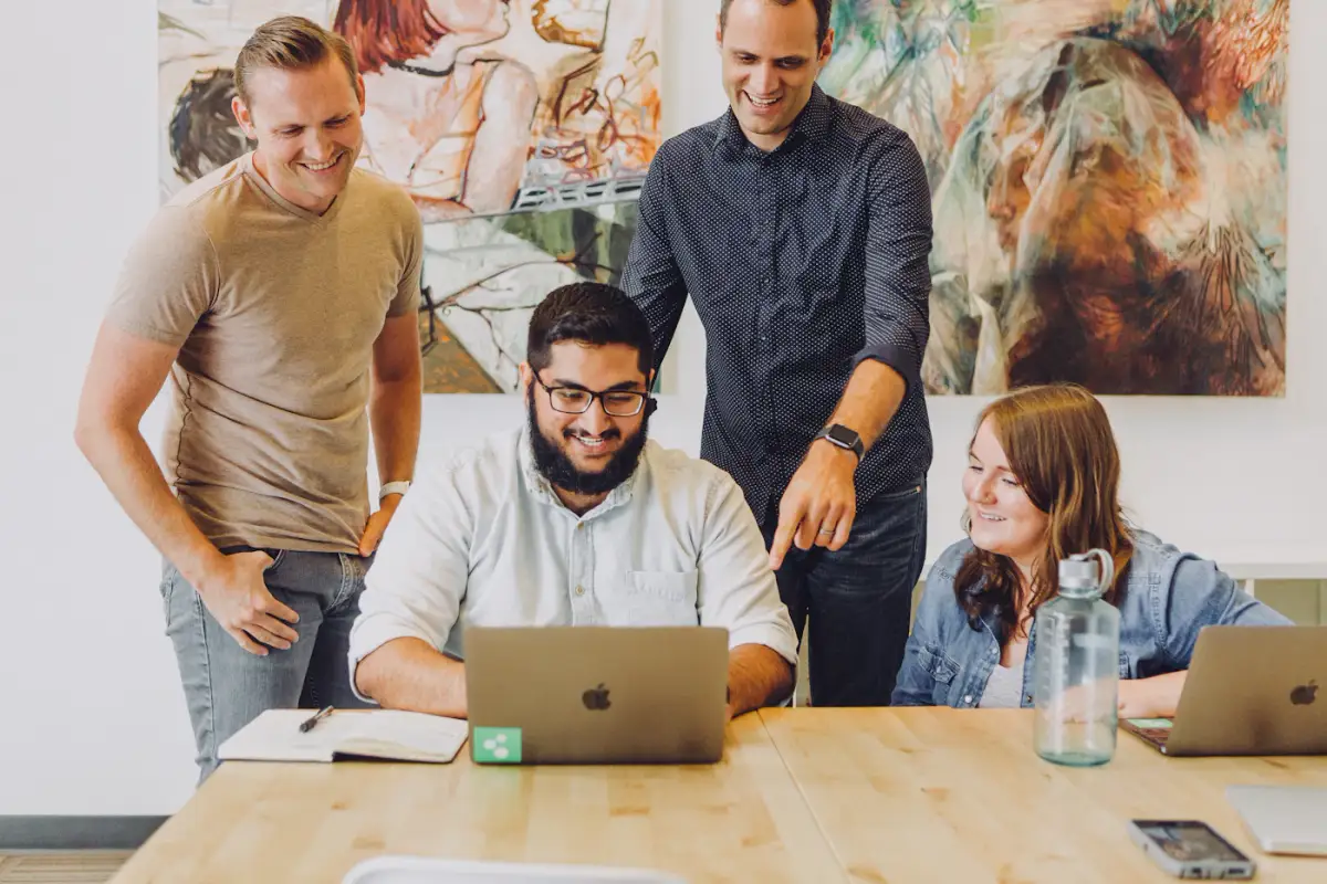 A sales team gathered around a laptop